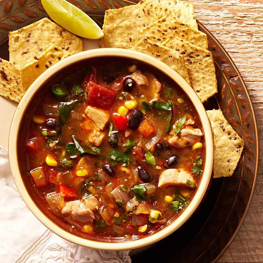 Bowl of soup with tortilla chips and lime on a wooden table