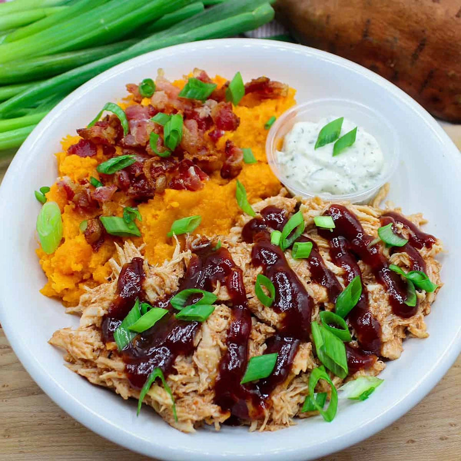 Plate of barbecue chicken and sweet potato mash with green onions.