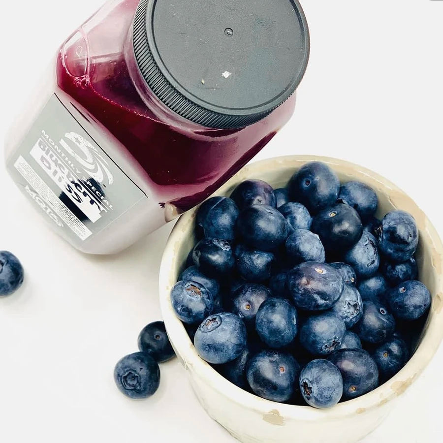 Bowl of blueberries next to a bottle of juice