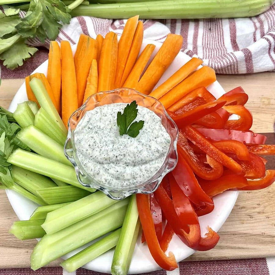 Platter of sliced vegetables with a bowl of ranch on a wooden surface