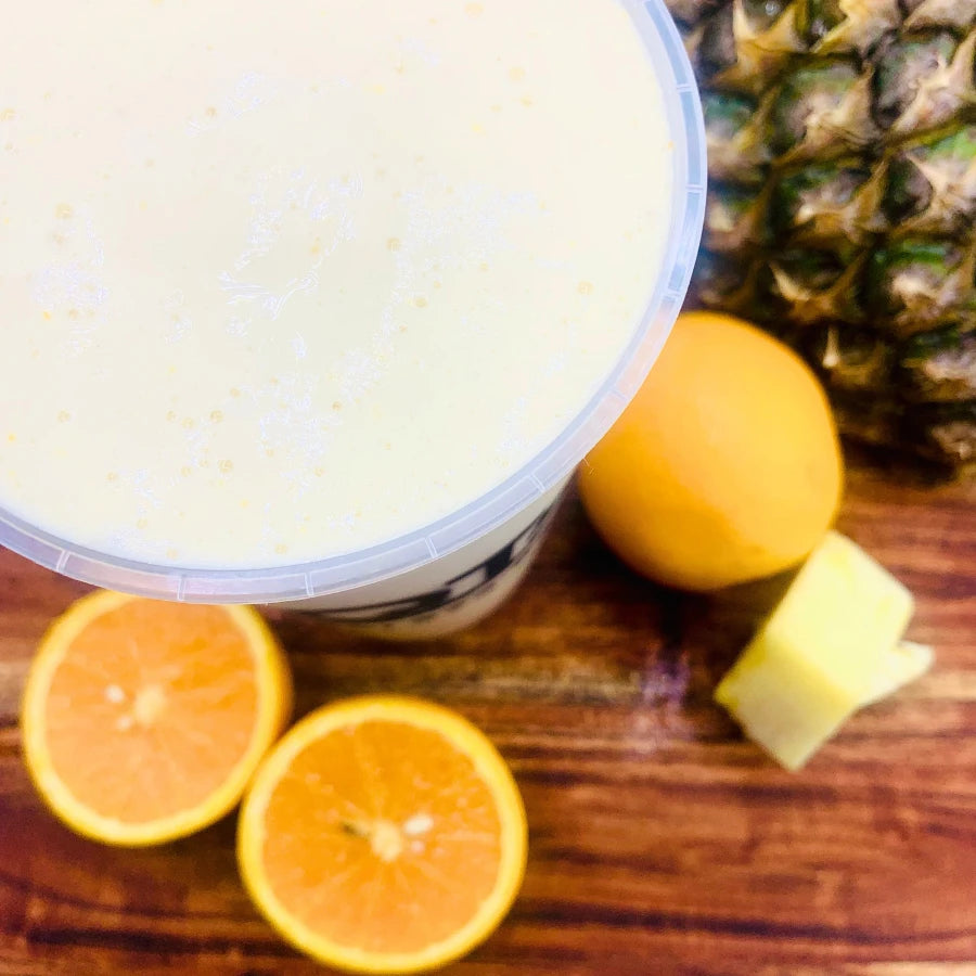 Smoothie with oranges and a pineapple on a wooden surface