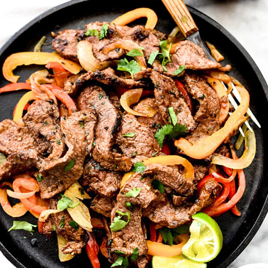 Fajita-style beef with bell peppers and onions on a black plate.
