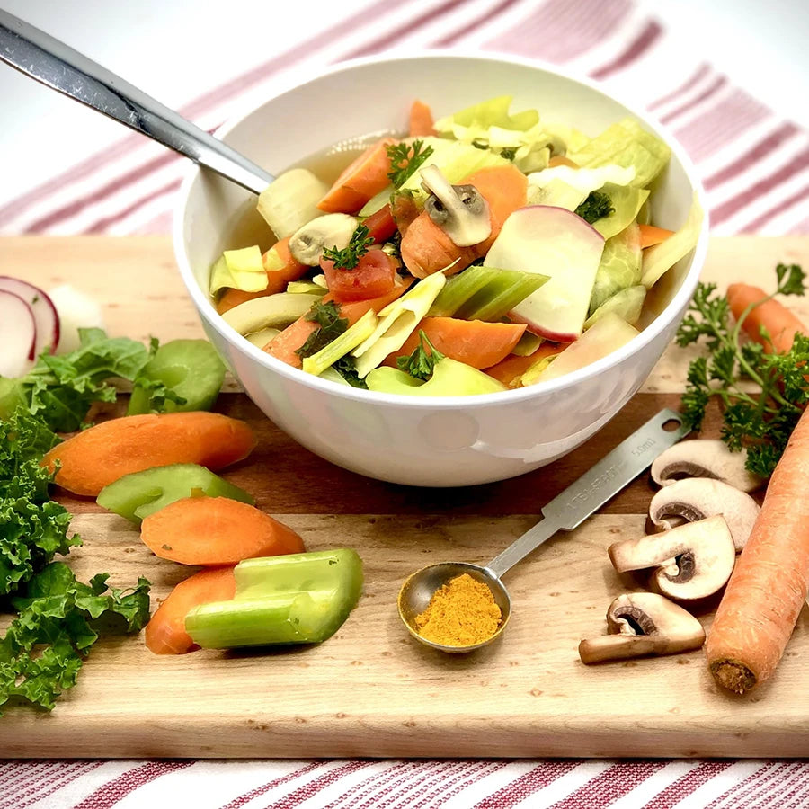 Bowl of vegetable soup with ingredients on a wooden board