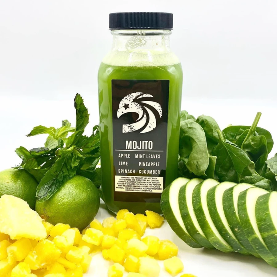 Bottle of green juice with ingredients like limes, spinach, and pineapple.