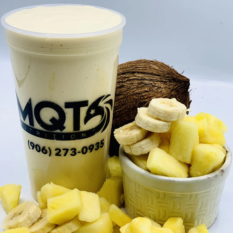 Smoothie in a cup, surrounded by pineapple and banana pieces.