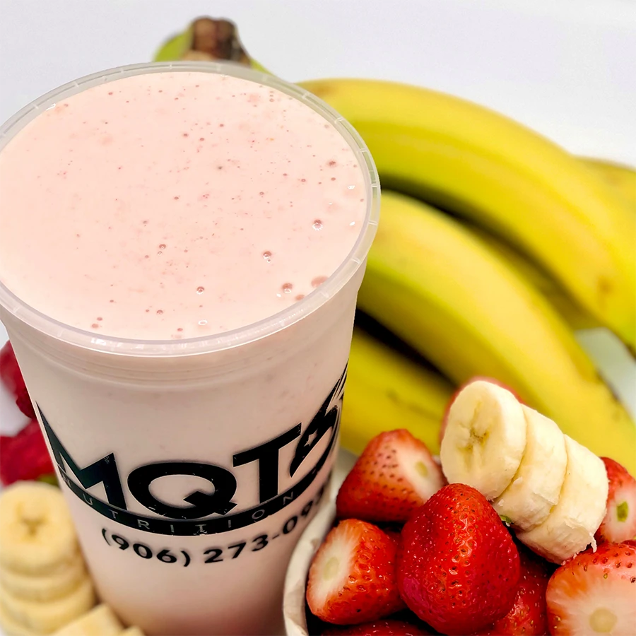 Pink smoothie in a cup with bananas and strawberries on a white background