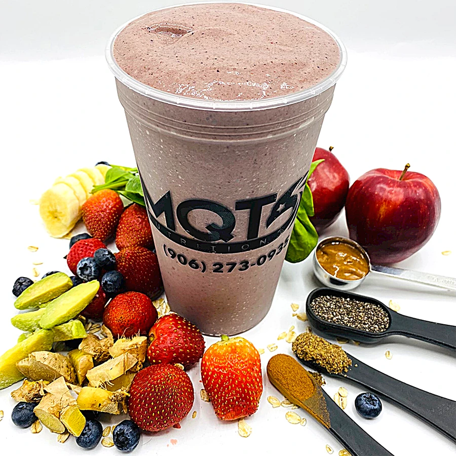 Protein smoothie in a clear cup with fruits and ingredients