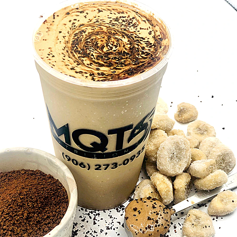 vnailla latte in a cup with cookies and coffee grounds on a white background