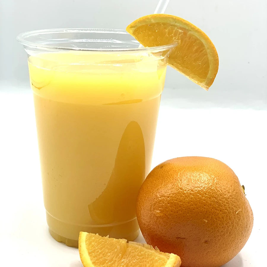 Clear plastic cup filled with orange juice, garnished with an orange slice, next to a whole orange.